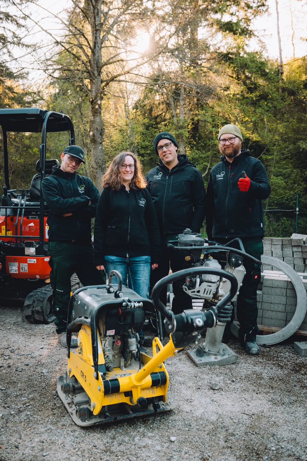 Teamfoto mit Minibagger und Rüttelplatte